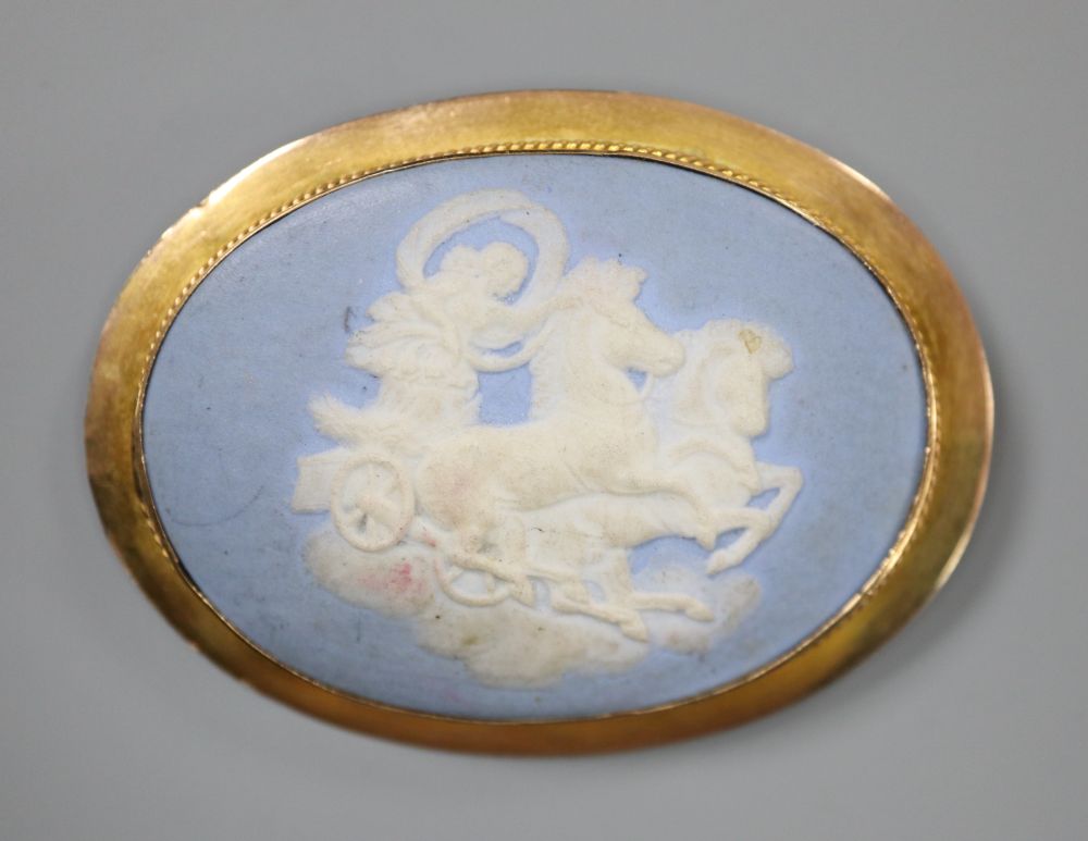 A late Victorian yellow metal mounted oval Wedgwood plaque brooch, depicting a maiden with chariot and horses,